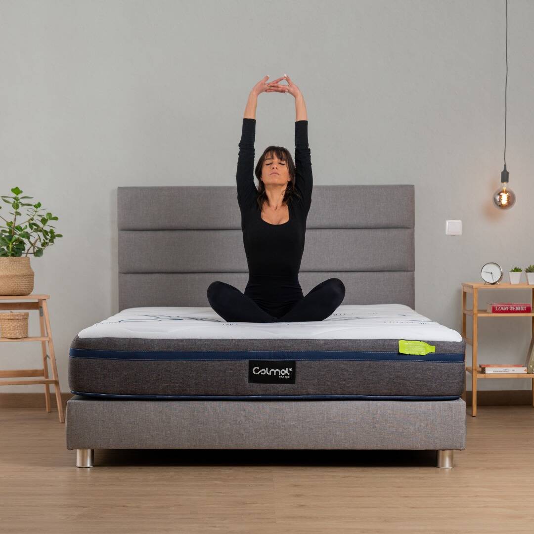 Pessoa sentada em cima de um colchão Colmol a espreguiçar-se para representar relaxamento